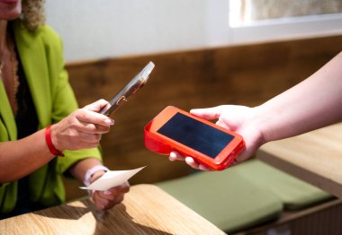 İş kadını restoranda akıllı telefon teknolojisiyle ödeme yapıyor.