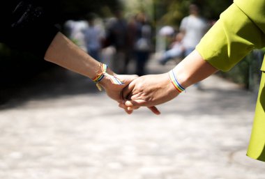 Çift el ele tutuşuyor, gökkuşağı bilezikleri takıyor, lgbtq + gururunu, sevgisini ve desteğini simgeliyor.