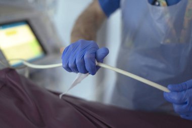 Doktor tüpü tutuyor, hastane odasında tıbbi bir prosedür için ekipman hazırlıyor.