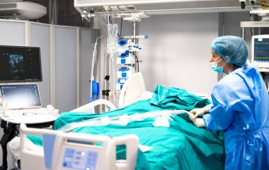 Cerrah, modern ameliyathanede gelişmiş tıbbi ekipman kullanarak hastayı ameliyata hazırlıyor.