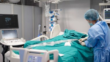 Ameliyathanede hasta bakımı yapan hemşire, ultrason cihazıyla tıbbi ekipmanlara bağlı.