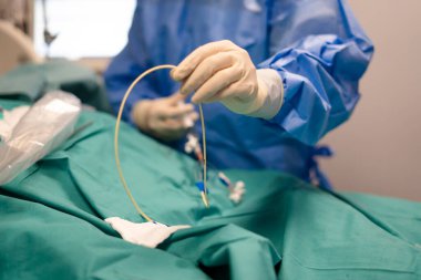 Steril eldiven takan bir cerrah tıbbi prosedür sırasında kateter takmaya hazırlanıyor.