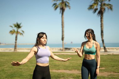 Güneşli bir günde plajın yakınındaki bir parkta spor yapan iki kadın.