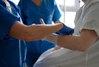 Tıbbi uzman, hastanın koluna bakımı ve bandajı yapar, düzgün bir şekilde iyileşmesini ve hijyeni sağlar.