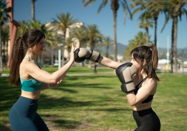 Parkta boks antrenmanı yapan iki bayan sporcu.