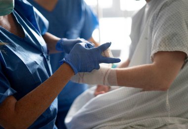 Tıbbi yardım sağlama, hastane ortamında hastanın kolunu sarma.