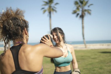 Açık havada boks antrenmanı yapan iki bayan sporcu deniz kenarında antrenman yapıyor.