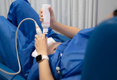 Doktor hamile karnı taramak için ultrason dönüştürücü ve tıbbi jel hazırlıyor.
