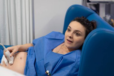 Doktor hamile bir kadının karnına ultrason yapıyor.