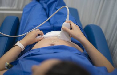 Jinekolog, ultrason çevirici kullanarak hamile kadını muayene ediyor.