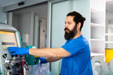 Modern bir hastanede diyaliz makinesini yöneten doktor böbrek yetmezliği olan hastalara gerekli bakımı sağlıyor.