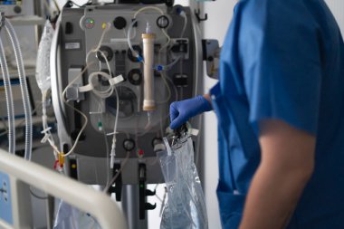 Hastane odasında bir hasta için diyaliz makinesi kullanan bir doktor.
