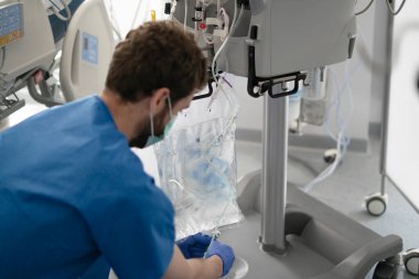 Doktor damar içi tedavi için tuz çözeltisi içeren infüzyon torbasını ayarlıyor.