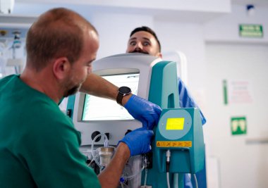 Diyaliz makinesini ayarlayan bir doktor bir hastanın tedavisi için bir hastane odasında hazırlanıyor.