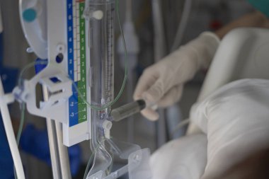 Tıbbi profesyonellerin seruma ilaç enjekte etmesi, hastane ortamında kritik bakım prosedürleri göstermesi.