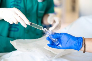 Tıbbi ekip steril ortamda cerrahi bir operasyon sırasında test tüpüne sıvı enjekte ediyor.