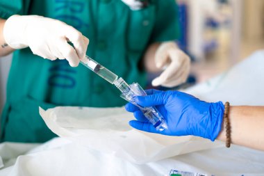 Tıbbi uzman, serum solüsyonuna ilaç enjekte ediyor. Hastane ameliyathanesinde cerrahi müdahaleye hazırlanıyor.