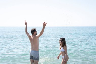 Mutlu çift okyanusa sıçrıyor, güzel güneşli bir günde yaz tatilinin tadını çıkarıyorlar.