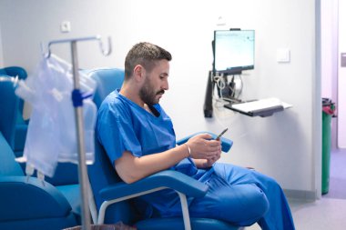 Damar içi tedavi görürken akıllı telefon kullanan, modern sağlık hizmetleri ve teknoloji entegrasyonunu gösteren bir hasta.