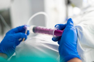 Eldivenli eller şırınga kullanıyor, hastane ortamında ilaç veriyor.