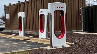 Tesla Supercharger 'lar boş bir arsada nöbet tutuyorlar. Parlak beyaz kuleleri ve parlak kırmızı limanları elektrik geleceğimizin bir sonraki yolculuğuna çıkmaya hazır..