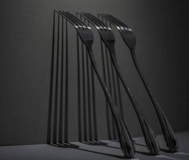Üç metal çatal keskin, ritmik gölgeler oluşturur minimalist bir yaşam kompozisyonu içinde simetri, tekrarlama ve ışığı vurgular..