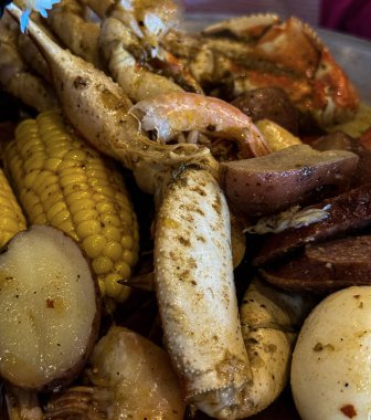 Yengeç bacağı, karides, mısır, kırmızı patates ve baharat içeren doyurucu bir deniz mahsulü haşlama, sıcak ve güney usulü bir ziyafette servis edilir..