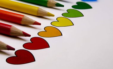 Renkli kalemler eğik bir eğimle uyumlu renkli kalplerle hizalanır. Eğitim için yaratıcı konsept, LGBTQ + gurur, sanat ve duygusal ifade.