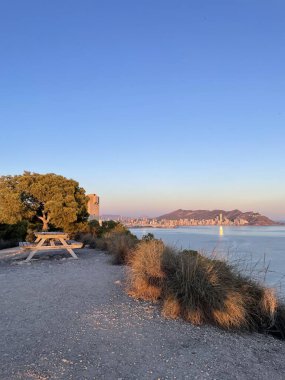 A resting spot on a hill with a view of the sea and the city coastline in Spain clipart