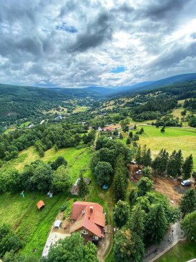 Göz kamaştırıcı bir dağ, bir vadi, yeşil tarlalar ve orman manzarası.