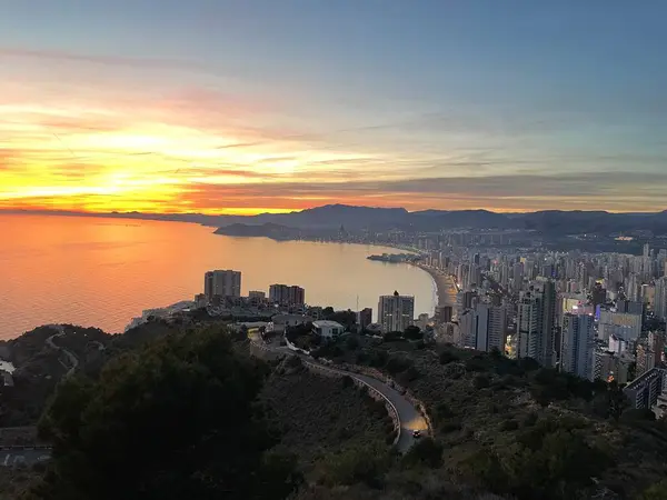 Romantik bir günbatımının tepesinden deniz ve dağların üzerinden İspanyol kasabasının manzarası.