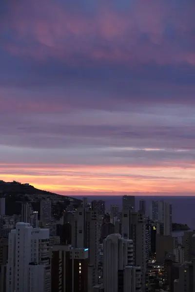 Denizin üzerinde inanılmaz bir gün doğumu ve bir İspanyol kasabasında binalar.