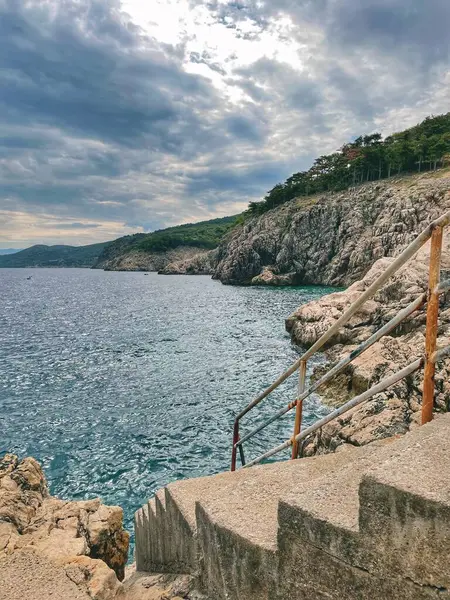 Bulutlu bir günde uçurumun kenarındaki sahile giden bir yol.