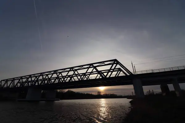 Nehir üzerinde gizemli bir demiryolu köprüsü, arkasında güzel bir günbatımı var.