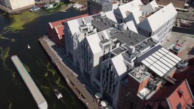 Bir nehrin drone görüntüsü ve turistik bir şehrin merkezindeki binaların yanında gezinti alanı.