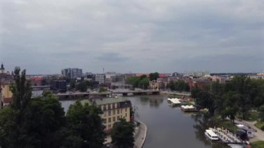 Eski bir kasabanın merkezindeki nehrin yukarısında, ağaçların ve arabaların geçtiği bir köprünün olduğu bir dron üstgeçidi.