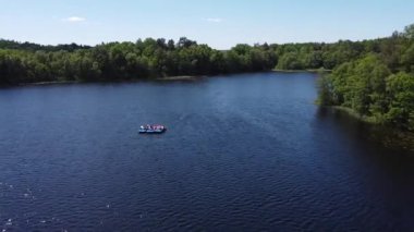 Yazın gölün üzerinde uçan dinamik bir drone, pedallı bir tekneye binen turistleri yakalıyor.