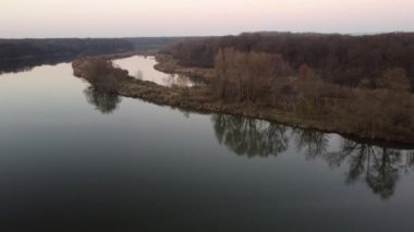 Gün batımında sisli bir günde, ormanı ve çevreyi ortaya çıkaran, bir insansız hava aracı bir nehrin üzerinde yükseliyor.