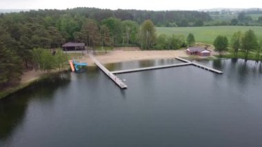 Bir gölün ve sisli bir günde ormanın manzarası olan boş bir plajın insansız hava aracı.