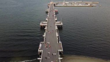 Deniz kıyısında bir rıhtımda turistlerle uçan bir İHA fotoğrafı.