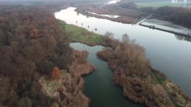 Sonbaharda nehir ve ormanlarla çevrili pitoresk bir noktaya inen bir dron görüntüsü.