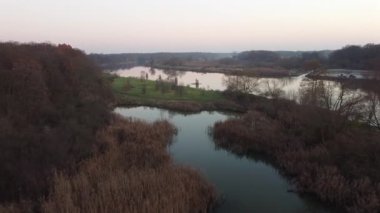 Sonbaharda bir orman ve nehrin yakınındaki göletin üzerinde uçan nostaljik bir dron.
