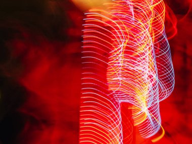 Kırmızı ve mavi soyut bir ışık gösterisi ve kırmızı bir arka plan. Kırmızı ve mavi ışıklar spiral bir şekilde hareket ediyor.