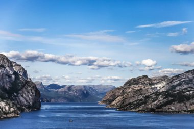 Norveç 'te berrak mavi bir gökyüzü ve sakin bir fiyort gölü olan güzel bir dağ sırası. Dağlar karla kaplı ve göl sakin ve huzurlu.