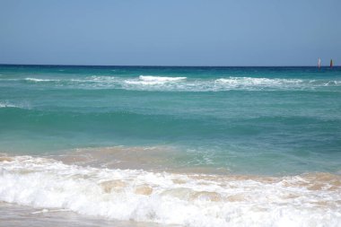 Fuerteventura İspanya 'da güzel mavi bir okyanus. Uzakta birkaç yelkenli var. Gökyüzü açık ve güneş parlıyor.