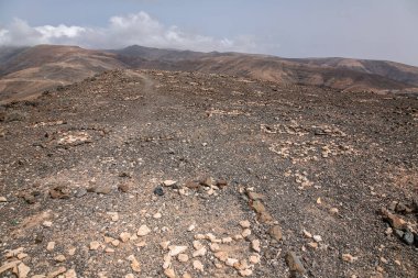 İspanya kanarya adaları. Toprak yolu olan kayalık bir yamaç. Yol asfaltlanmamış. Bölgede ağaç ya da bitki örtüsü yok.
