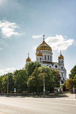 İsa, Moskova 'daki Kurtarıcı Katedrali. Üzerinde altın kubbeler ve altın bir haç olan büyük beyaz bir kilise. Kilise ağaçlarla çevrili ve bir caddede yer almaktadır.