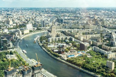 Moskova 'da içinden Moskova nehri akan bir şehir. Nehir binalar ve ağaçlarla çevrilidir. Nehirde kayıklar ve arka planda bir vinç var.