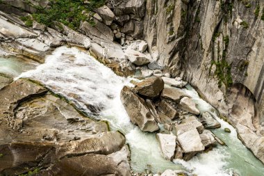 Şelalesi ve İsviçre 'de kayaları olan bir nehir. Su berrak ve kayalar beyaz.