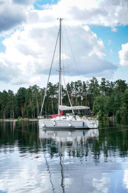 Sarı bir yelkenli Rusya 'nın güney Urallar' daki Turgoyak Gölü 'nde mavi bir teknenin yanına yanaşır. Suda başka tekneler de var.